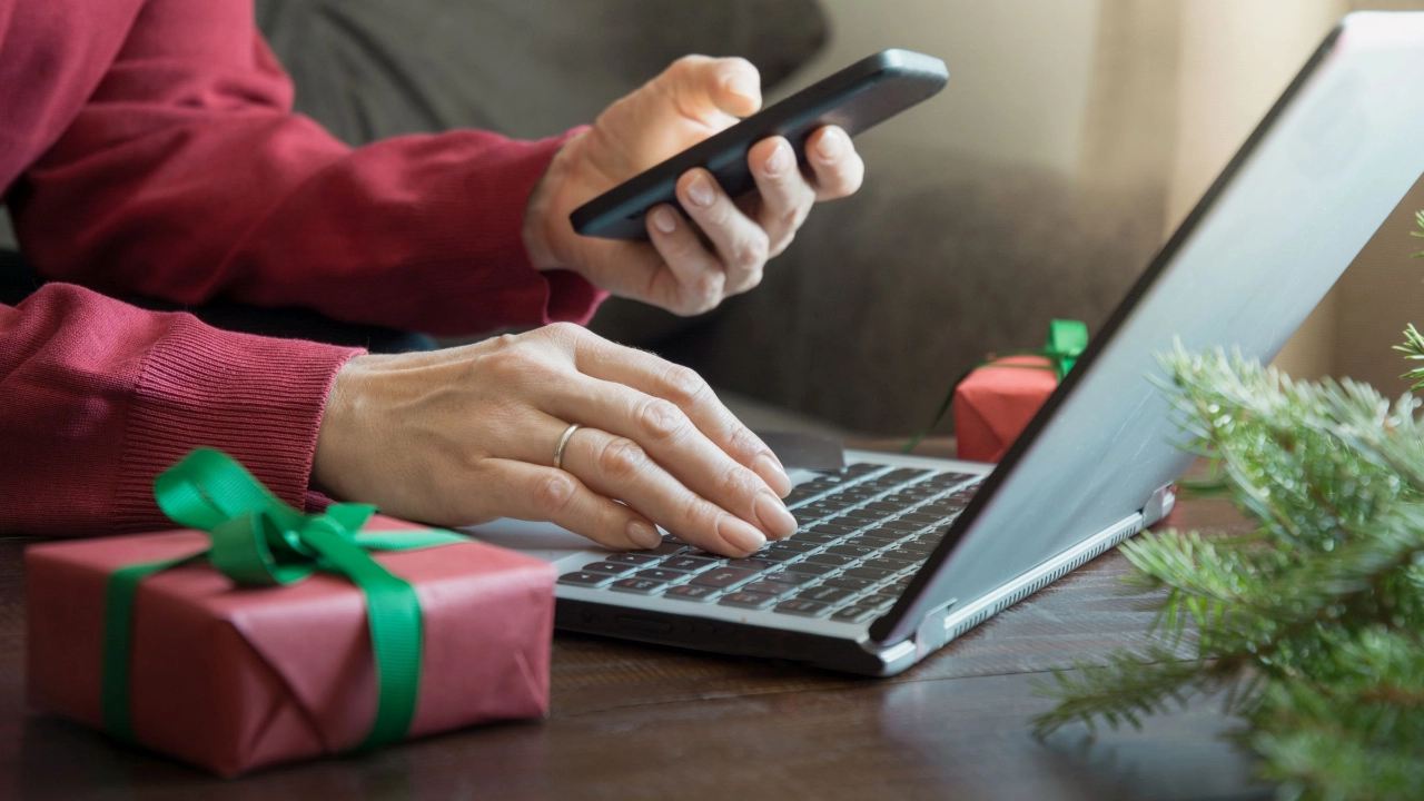 Beschäftigte:r mit Smartphone an einem Laptop