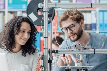 Zwei junge Ingenieure arbeiten an einem 3D-Drucker.