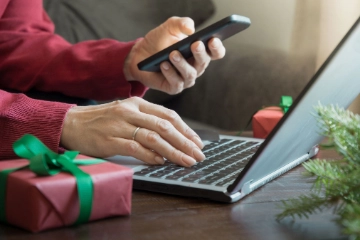 Beschäftigte:r mit Smartphone an einem Laptop